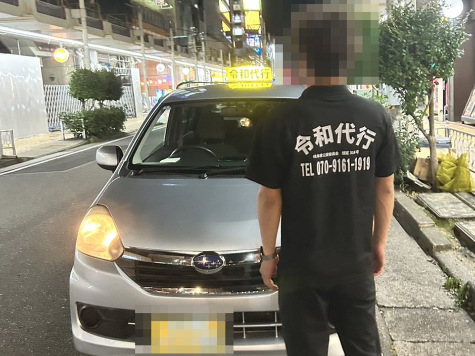 令和代行のユニフォームを着たスタッフの後ろ姿と随伴車。